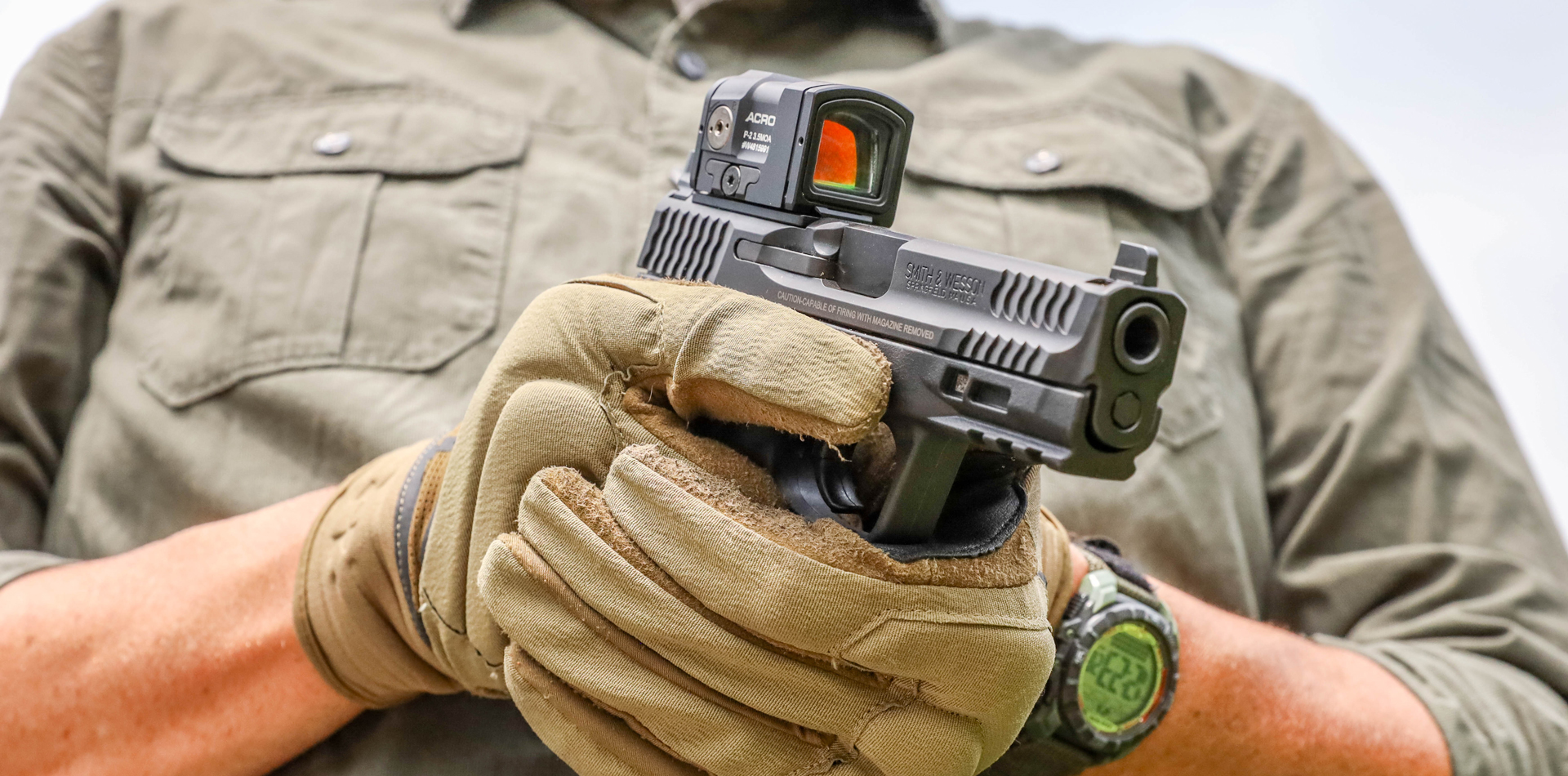 Photo of a man holding a pistol with a red dot sight attached
